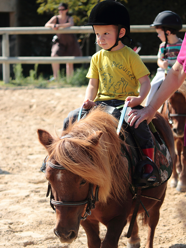 Un enfant se balade à dos de poney.